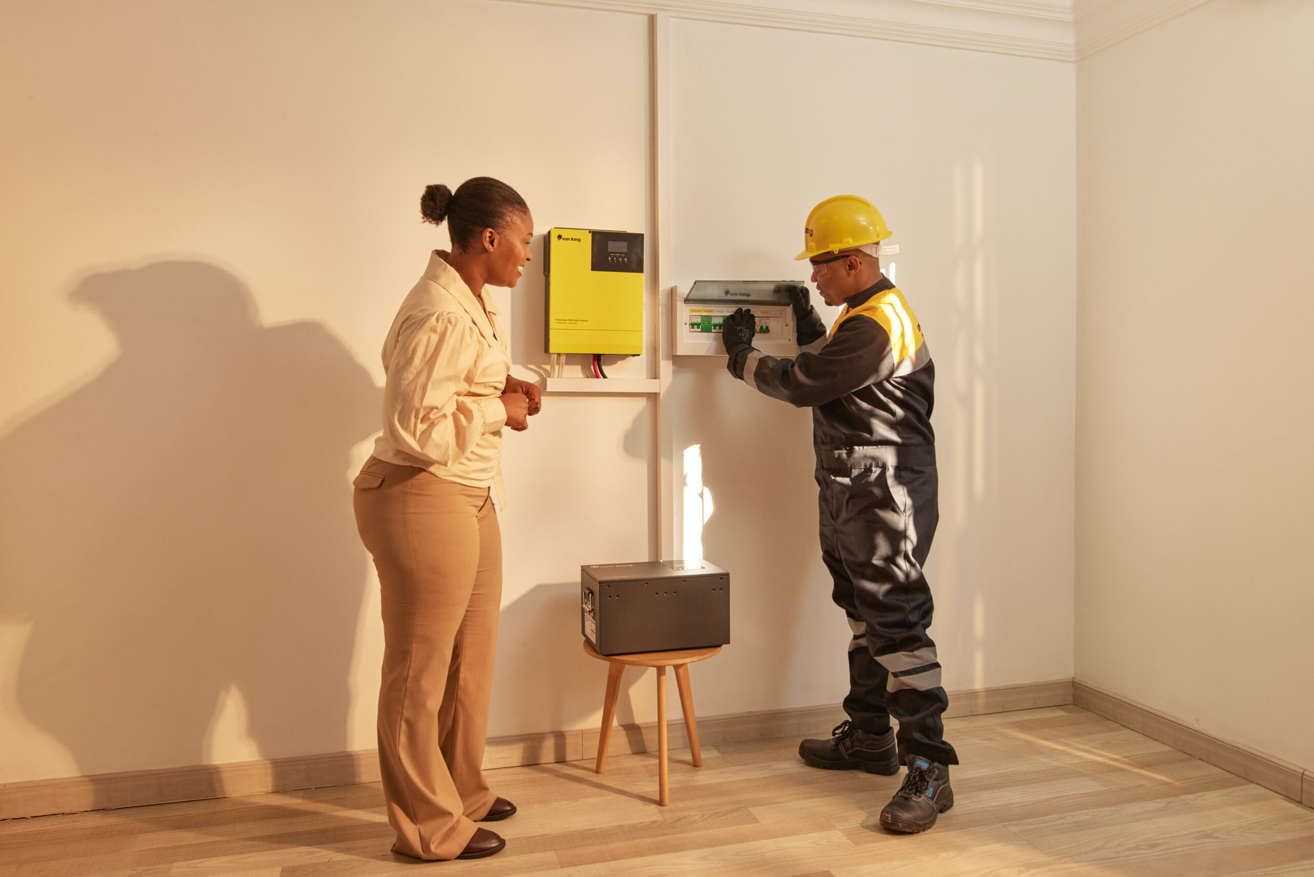 A customer interacting with a Sun King employee during a solar inverter system installation.